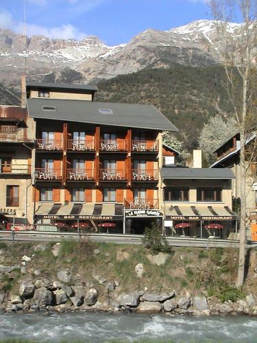 瓦卢伊斯Chambre Triple avec Salle de Bains Privative 2的山前有河流的酒店建筑