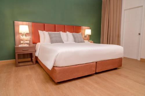 曼谷Legacy Hotel Bangkok Sukhumvit的一张大床,位于酒店带两盏灯的房间