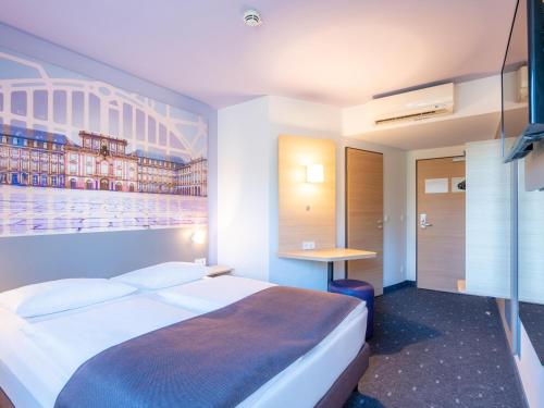 曼海姆B&B Hotel Mannheim的酒店客房设有一张大床和一张书桌。