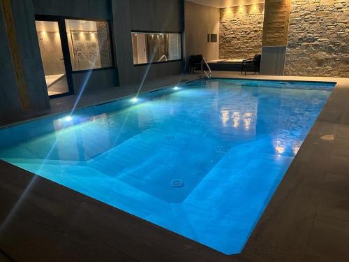 莱热Hôtel Alpina & SPA的一座大型蓝色游泳池,灯光照亮