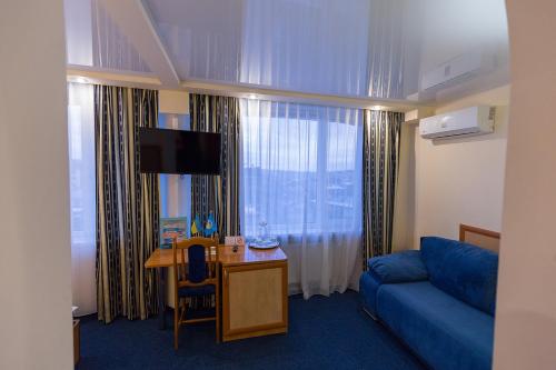 特鲁斯卡韦茨Truskavets 365 Hotel的酒店客房配有蓝色的沙发、书桌和电视。