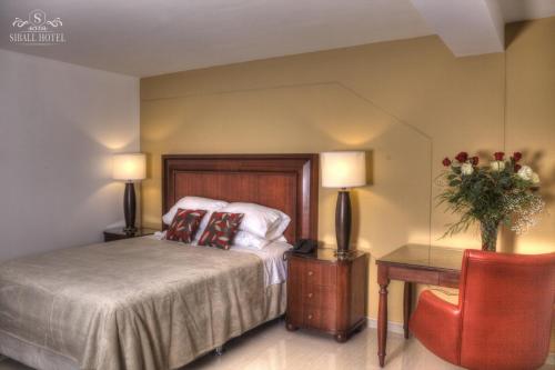Abancay斯巴尔酒店的一间卧室配有一张床、一张桌子和两盏灯。