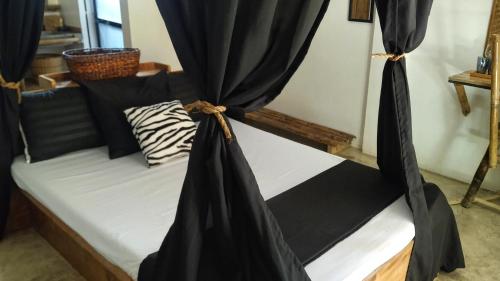 卢纳将军城Tarzan's House的一张带黑色窗帘的床