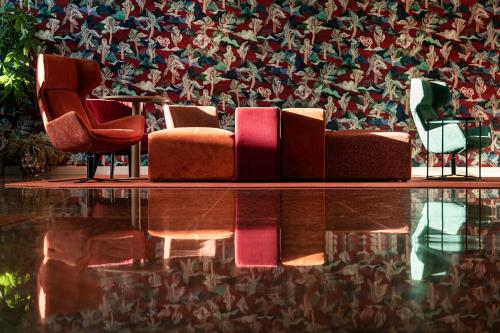米兰Quark Hotel Milano的一间设有三把椅子、一张桌子和一张壁纸的房间