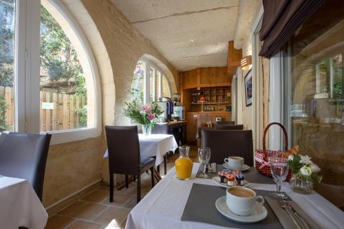 萨尔拉拉卡内达La Villa des Consuls - Gîte de tourisme de charme的一间设有两张桌子和窗户的用餐室