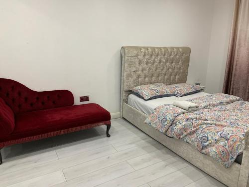 海维康Inviting 2-Bed fully Furnished House-High Wycombe的一间卧室配有一张床和一张红色的沙发