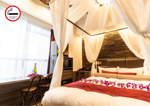 东京BaliAn Resort Forest Ikebukuro的一间卧室配有一张带窗帘和桌子的天蓬床。