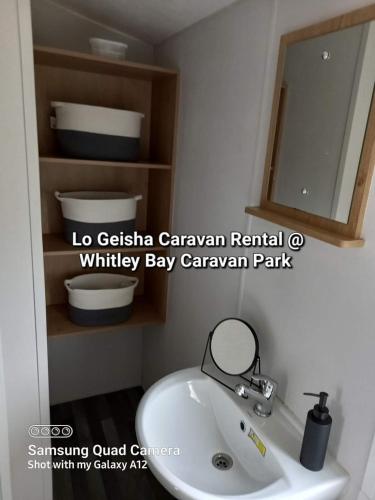 惠特利湾Lo Geisha Caravan Rental at Whitley Bay Caravan Park的浴室设有白色水槽和镜子