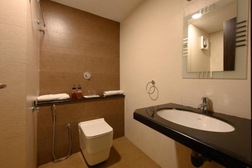 昆达普拉Hotel Samudyatha Inn And Suites的一间带水槽、卫生间和镜子的浴室