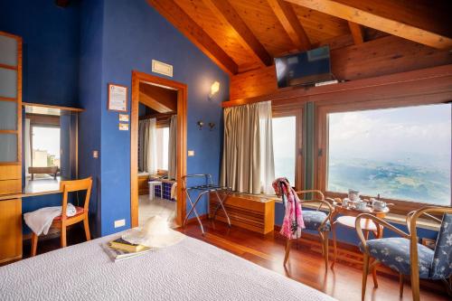 圣马力诺切萨雷酒店的卧室设有蓝色的墙壁、桌子和大窗户
