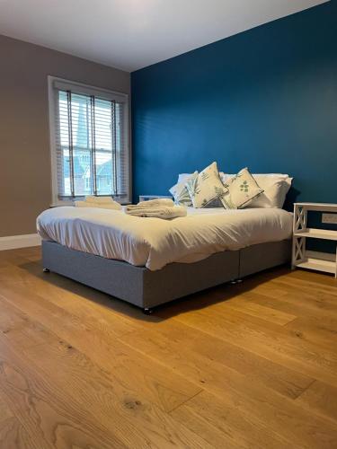 圣艾夫斯Two Bedroom Duplex Apartment The Priory的卧室内的一张床铺,卧室内有蓝色的墙壁