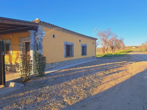 ArgésCasa Rural La Veguilla的一条黄楼,在路边有栅栏