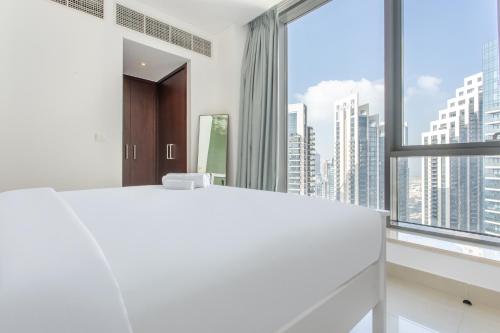 迪拜WeHost - Modern 1BR Close to Burj Khalifa and Dubai Mall的卧室设有一张白色大床和大窗户