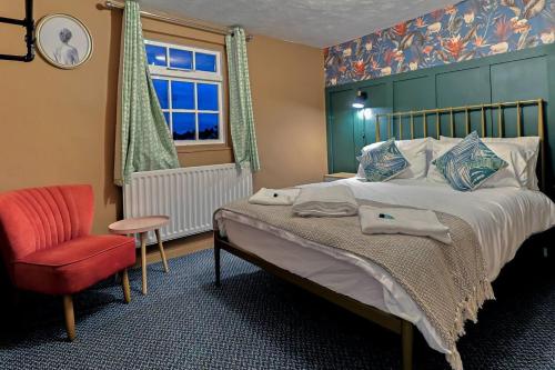 克劳奇河畔伯纳姆Beautiful 3-Bed Cottage in Burnham-on-Crouch的卧室配有床、椅子和窗户。