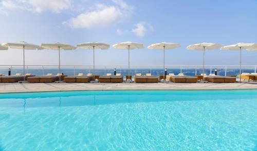 莫罗德哈布雷XQ帕拉赛特酒店的一座大楼内的游泳池,配有椅子和遮阳伞
