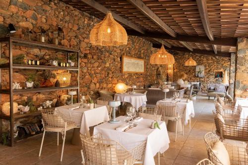 圣弗洛朗Hôtel La Dimora & Spa的一间设有白色桌椅和石墙的餐厅