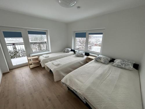 Radikiai House的一间带三张床和两扇窗户的卧室