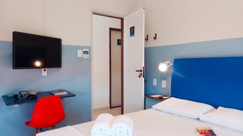 萨尔瓦多FAROL BEACH Apartamentos & Suítes的一间卧室配有一张床和一张红色椅子