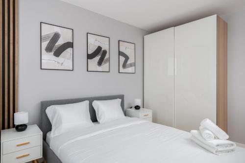 克拉科夫Tauron Modern Studio的一间白色的卧室,配有一张床和墙上的一些照片
