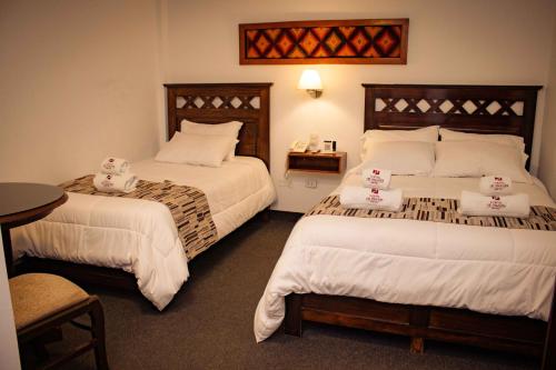 卡哈马卡El Portal Del Marques的酒店客房设有两张床和一张桌子。