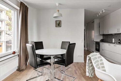 斯德哥尔摩Stylish Urban Home in Stockholm的厨房配有白色的桌子和黑色的椅子