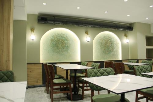 伊斯坦布尔Sabiha Sultan Hotel-Karakoy的餐厅设有桌椅和3扇拱形窗户