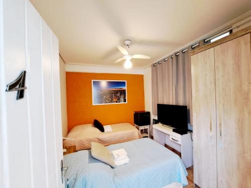 圣保罗SP Guest House的一间卧室配有两张床和一台平面电视