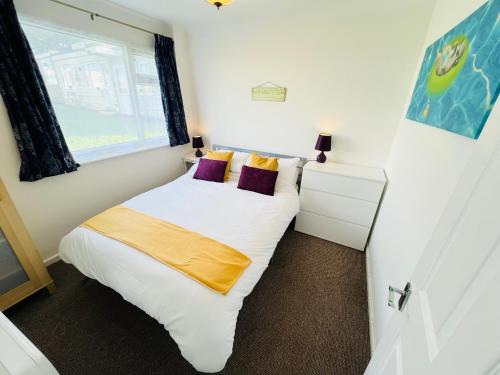 Brading2 Bedroom Chalet SB113, Sandown Bay, Isle of Wight的一间小卧室,配有白色的床和窗户