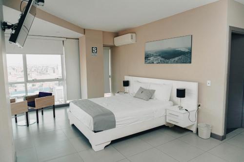 钦博特Hotel Viera Chimbote的卧室配有白色的床和桌椅
