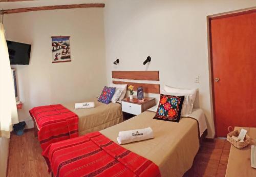 卢那欢纳La Fortaleza del Inca的酒店客房带两张床和红色的行李箱