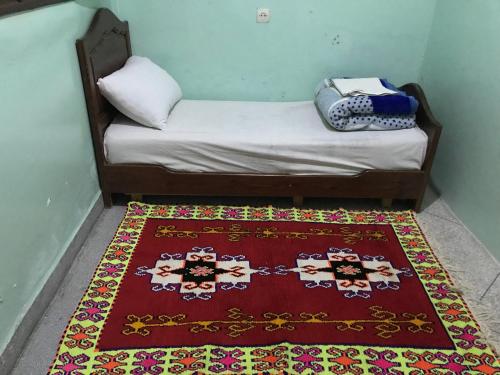 Tan-Tan PlageMaison d’hôtes ATLAS ait alla的一张小床,位于一间有地毯的房间