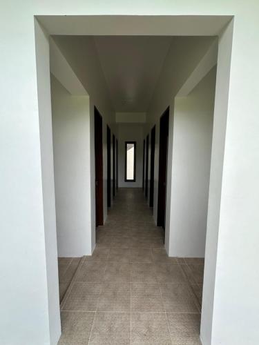 卢纳将军城Haven Suites Siargao的一条空的走廊,有白色的墙壁和瓷砖地板