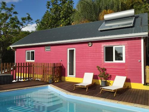 波尔兰特Kaz Kalina - Gîtes avec piscine partagée的粉红色的房子,配有两把椅子和游泳池