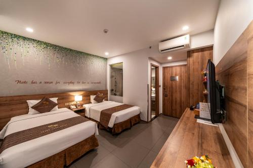 胡志明市Thanh Long Hotel - Tra Khuc的一间酒店客房,设有两张床和电视