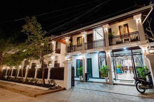 琅勃拉邦Cozy An Boutique Hotel Luangprabang的一辆摩托车停在前面,晚上的房子