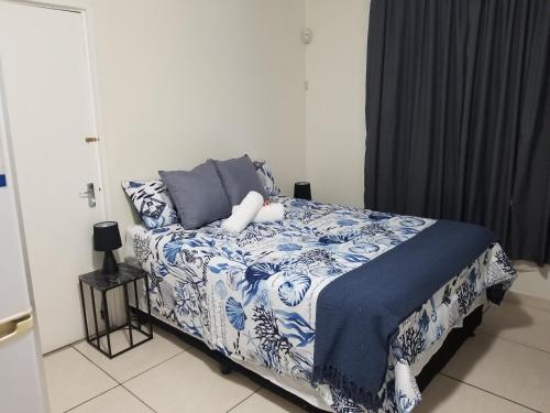 KingsboroughKiaatplace Holiday Apartment的一间卧室配有一张带蓝色和白色棉被的床