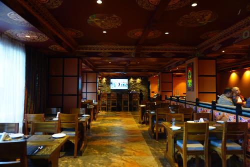 大吉岭Gakhil Boutique Hotel的餐厅设有木桌、椅子和电视