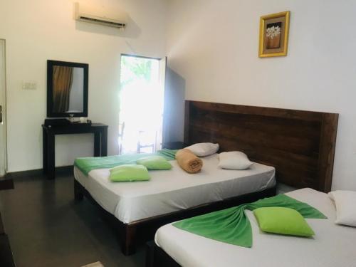 波隆纳鲁沃Polonnaruwa Holiday Inn的一间卧室配有两张带绿色和白色枕头的床