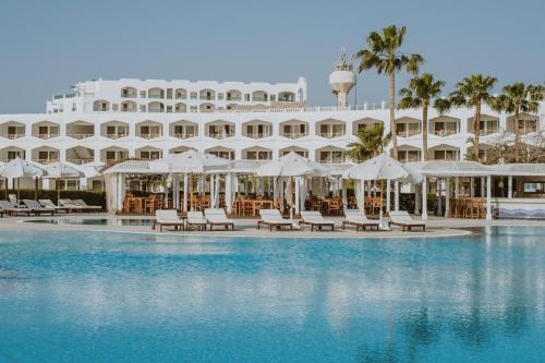 沙姆沙伊赫沙姆沙伊赫巴伦度假酒店的游泳池旁的酒店拥有椅子和遮阳伞