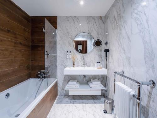 蒂涅Hôtel Le Diamond Rock的一间带水槽、浴缸和镜子的浴室