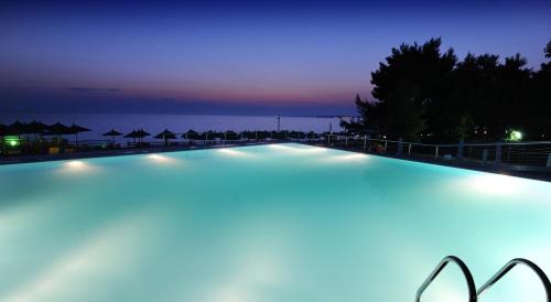 尼坡帝伊斯申俱乐部Spa酒店的夜晚的游泳池,背景是大海