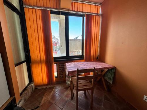 帕坦loo niva guest house studio apartment with balcony的窗户房间里一张桌子和一把椅子