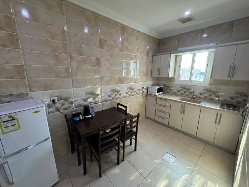 吉达PRIMOTEL Suites As Salamah的厨房配有桌子和白色冰箱。