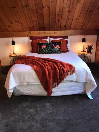 下哈特Comfort and Style in this Petone Townhouse的卧室配有一张带红色毯子的白色床
