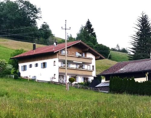 容霍尔茨Jungholz Erlebnis的山坡上一座白色房子,屋顶红色