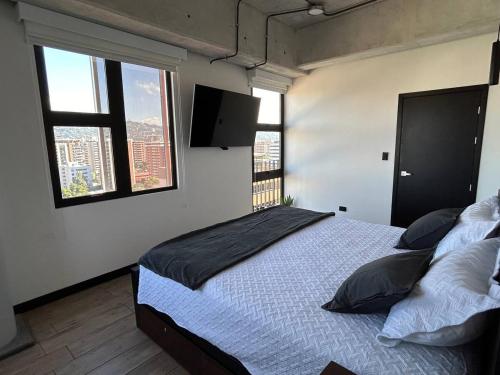 危地马拉EÓN 13 - Apto moderno con aire acondicionado的一间卧室设有一张床和两个窗户。