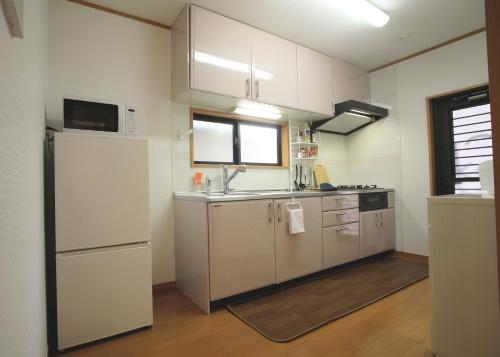 Takagiたび宿SeKKoku的厨房配有白色橱柜、水槽和冰箱。