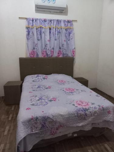 恩卡纳西翁Hospedaje 3 DE MAYO的一间卧室配有一张带紫色棉被的床和窗户。