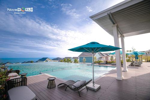 潘切Seamoni Seaview Villa 02 - Novaworld Phan Thiết的一个带椅子和遮阳伞的甲板和一个游泳池