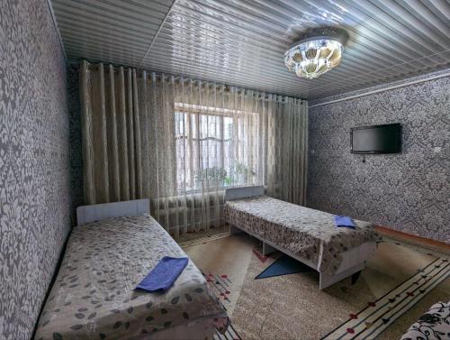 卡拉科尔Olzho Hostel的一间带两张床的卧室和一台电视